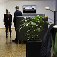 Two persons talking by the information screen in an office landscape