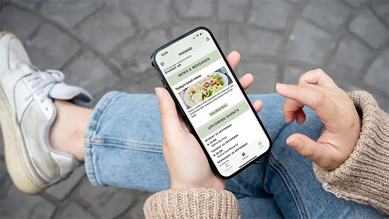 A student holding a phone with PinToMind Go open, showing a dedicated channel with relevant updates for high school students. Photo.