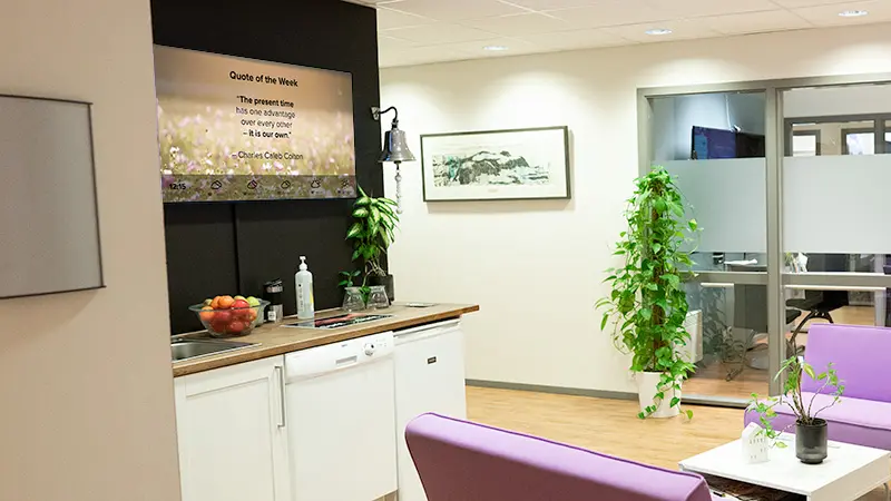 A common area in an open office solution, where a digital notice board is displaying a quote. Photo.